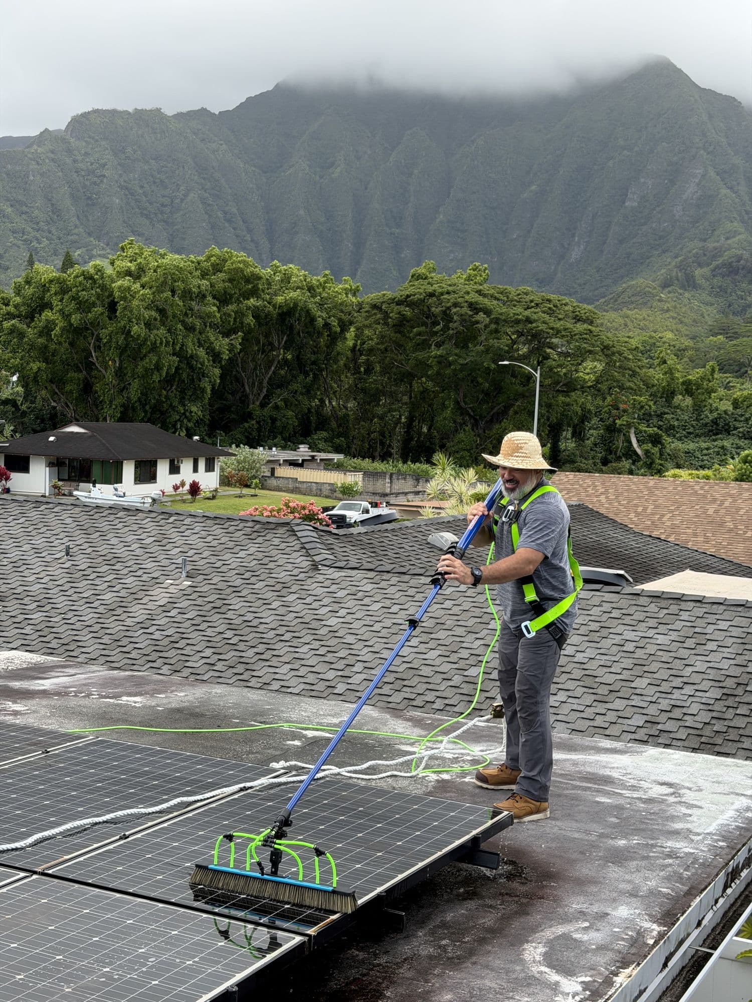 Ari cleaning solar panels with the Ko'olau behind him