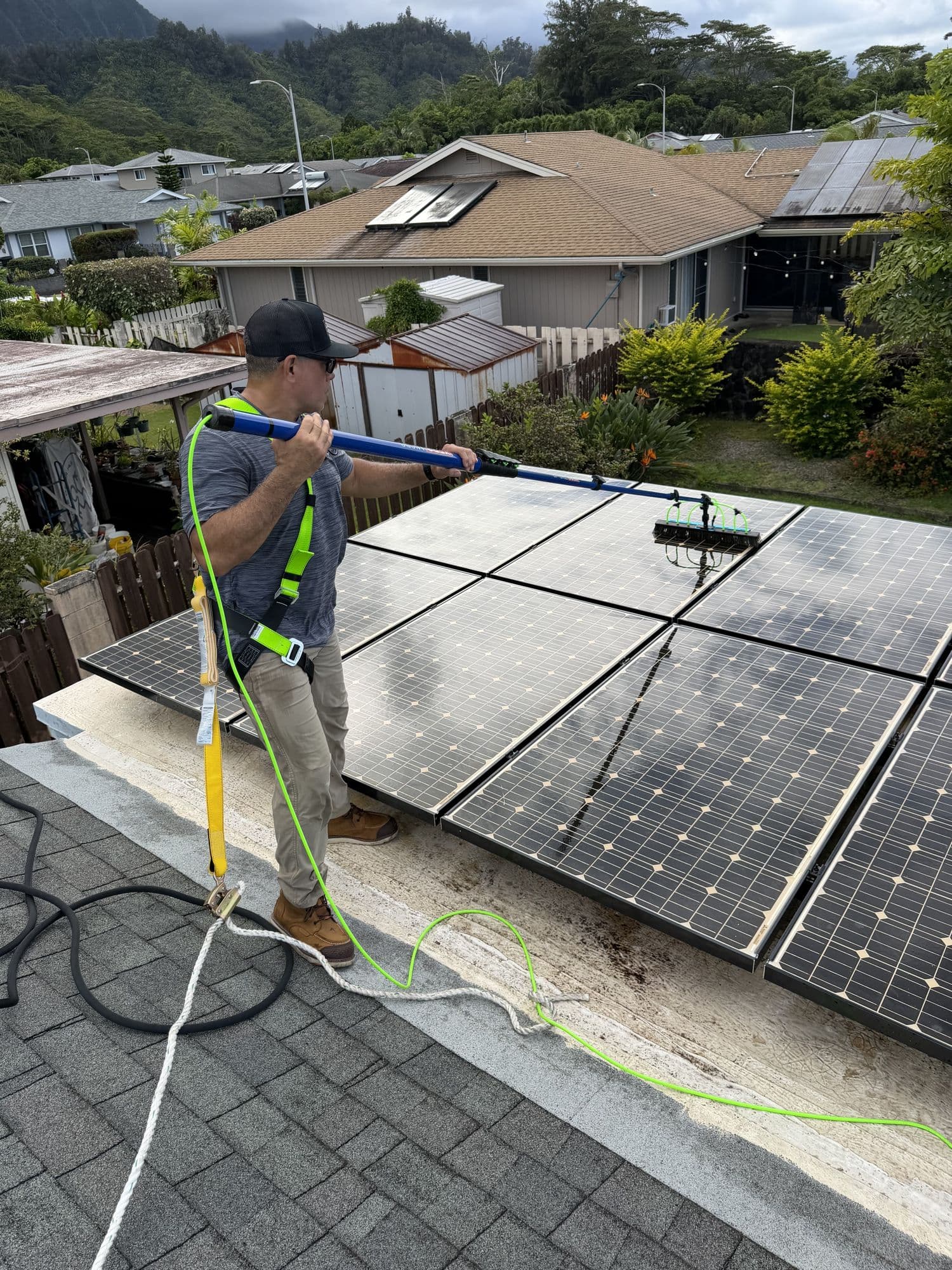 Ari working a water-fed brush across a solar array